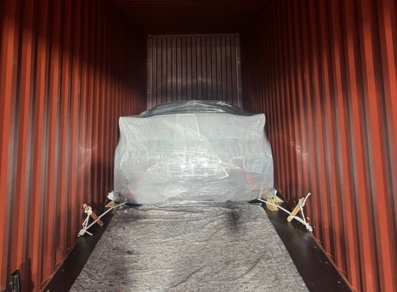 A wrapped vehicle secured inside the container, ready for dispatch